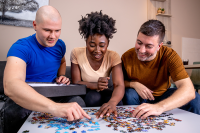 Two men and a woman working on a puzzle