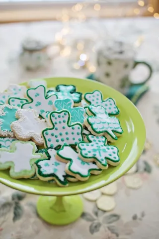 Shamrock shaped cookies decorated with icing on a green serving tray.