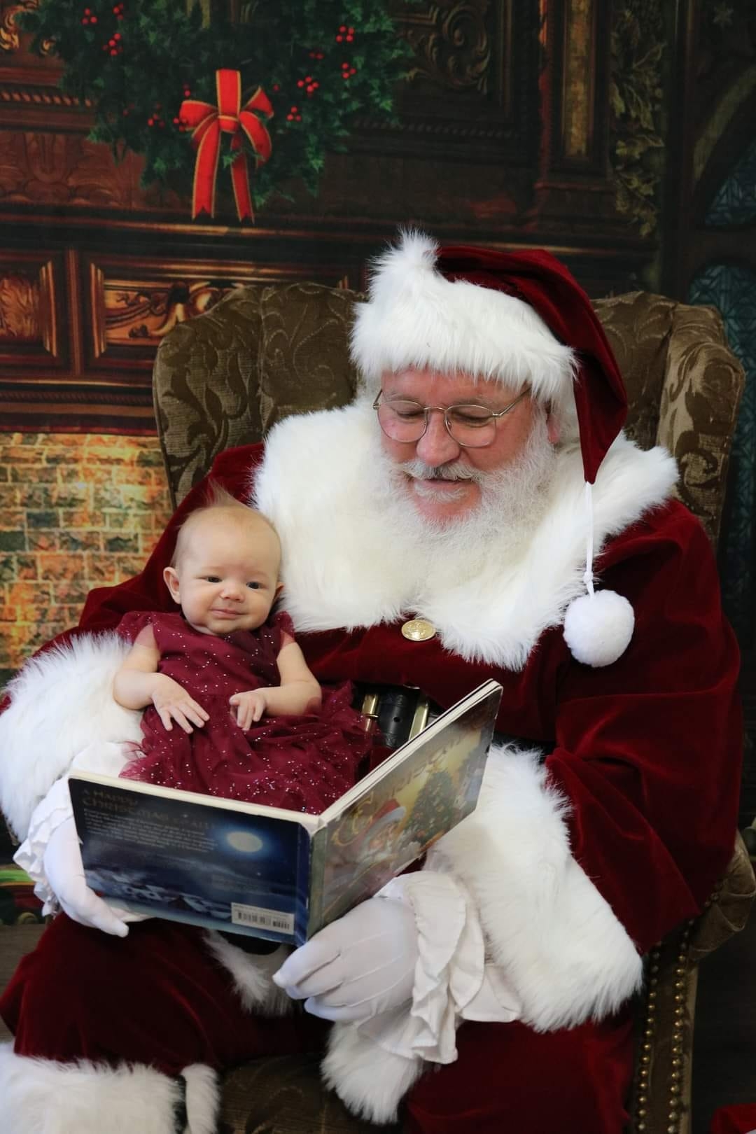 Santa Clause reading to a child on his lap. 
